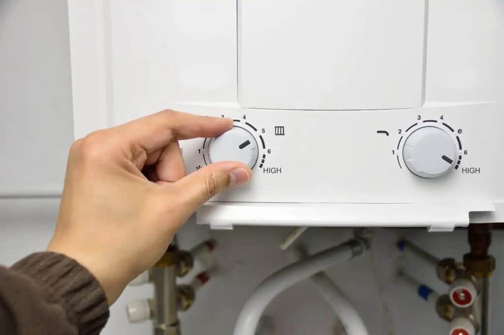 Hand adjusting a knob on a tankless water heater.