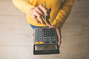 Woman using a calculator with a pen in her hand, calculating how much money she can save through 25C tax credits